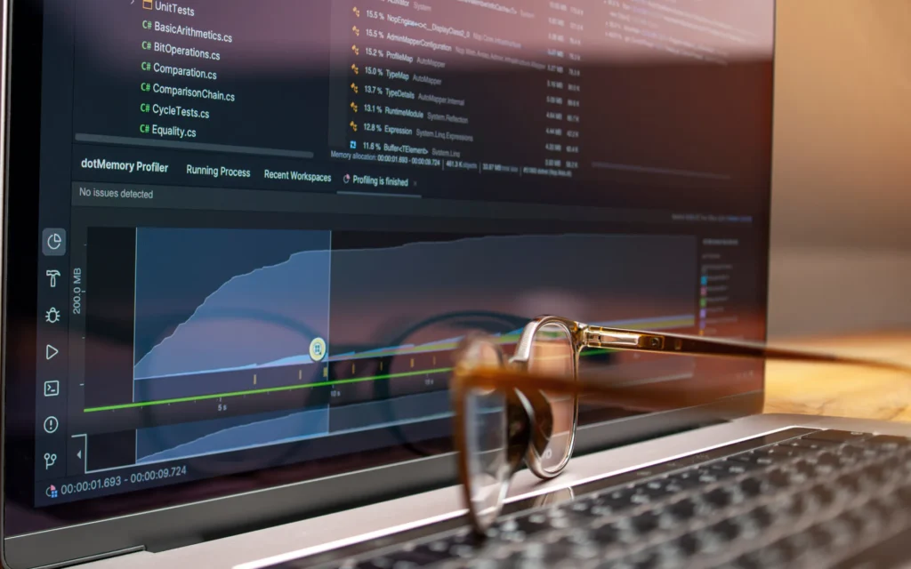 Ordenador portátil con herramientas de programación y unas gafas sobre el teclado.