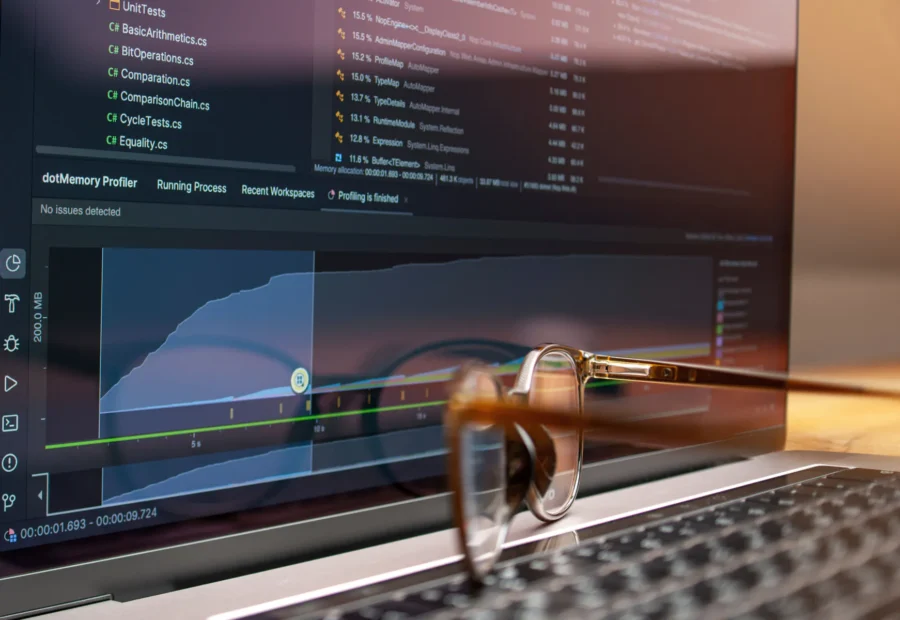 Ordenador portátil con herramientas de programación y unas gafas sobre el teclado.