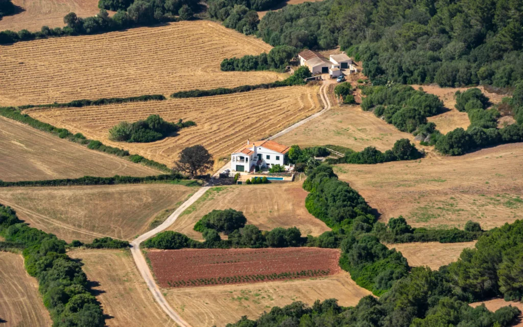 Vista aérea de campos de cultivo y viviendas rodeadas de árboles.