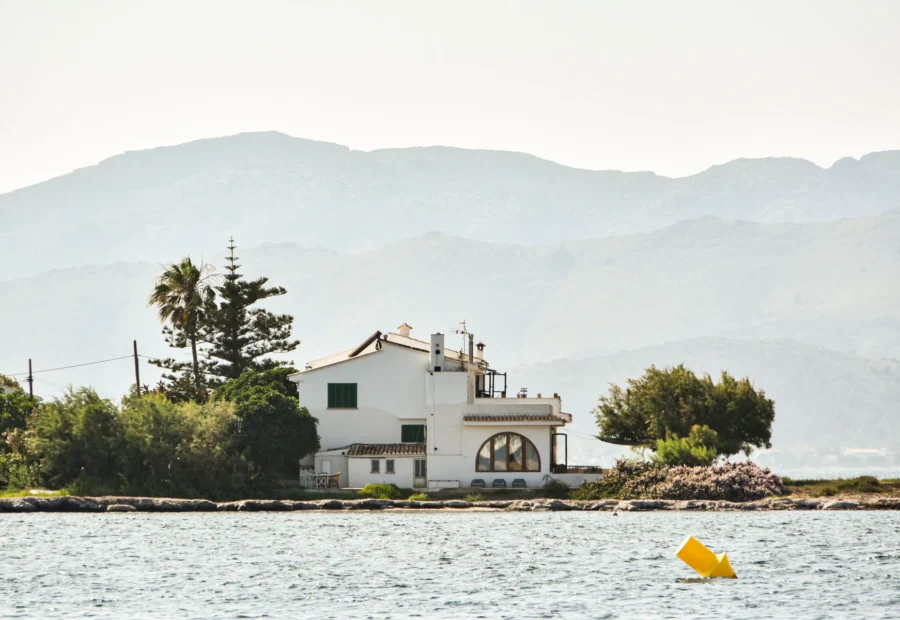 Casa blanca junto al mar con montañas al fondo.